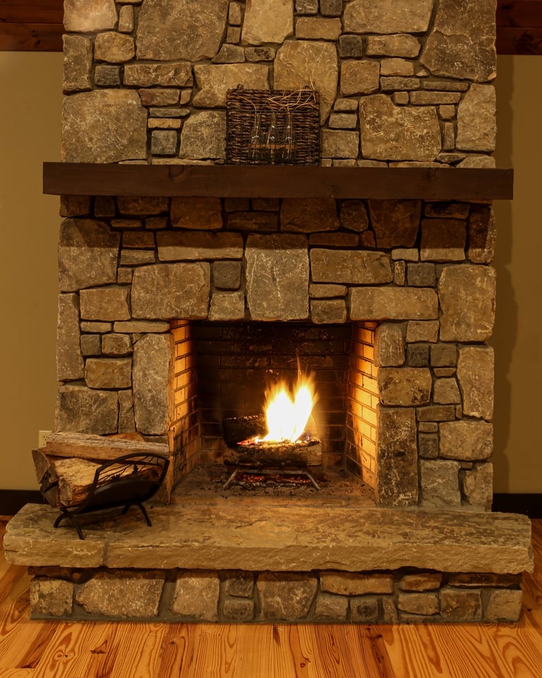 Warm, cozy fire in the large stone fireplace in the cabin in the mountains