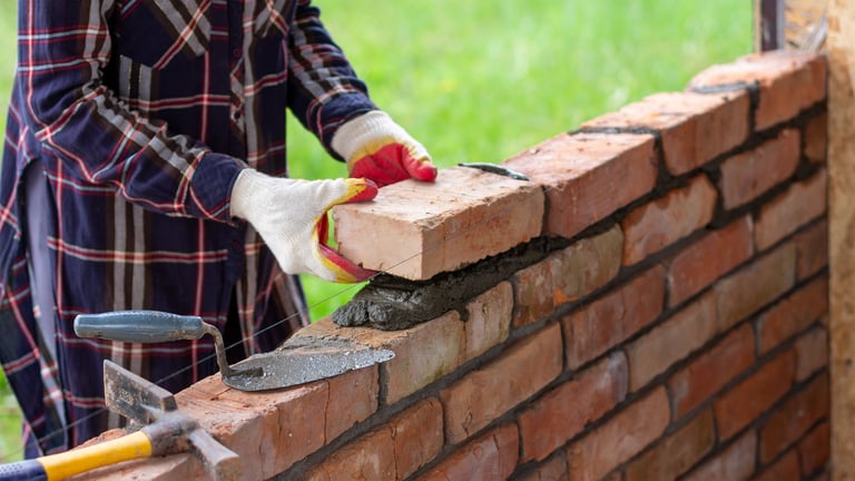 A young female bricklayer builds a wall