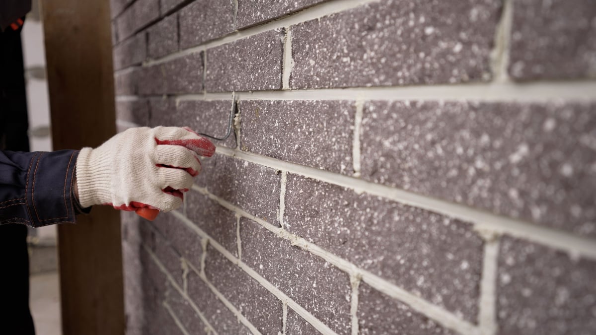 The worker wipes the brickwork of the wall, the bricklayer wipes the seam between the bricks