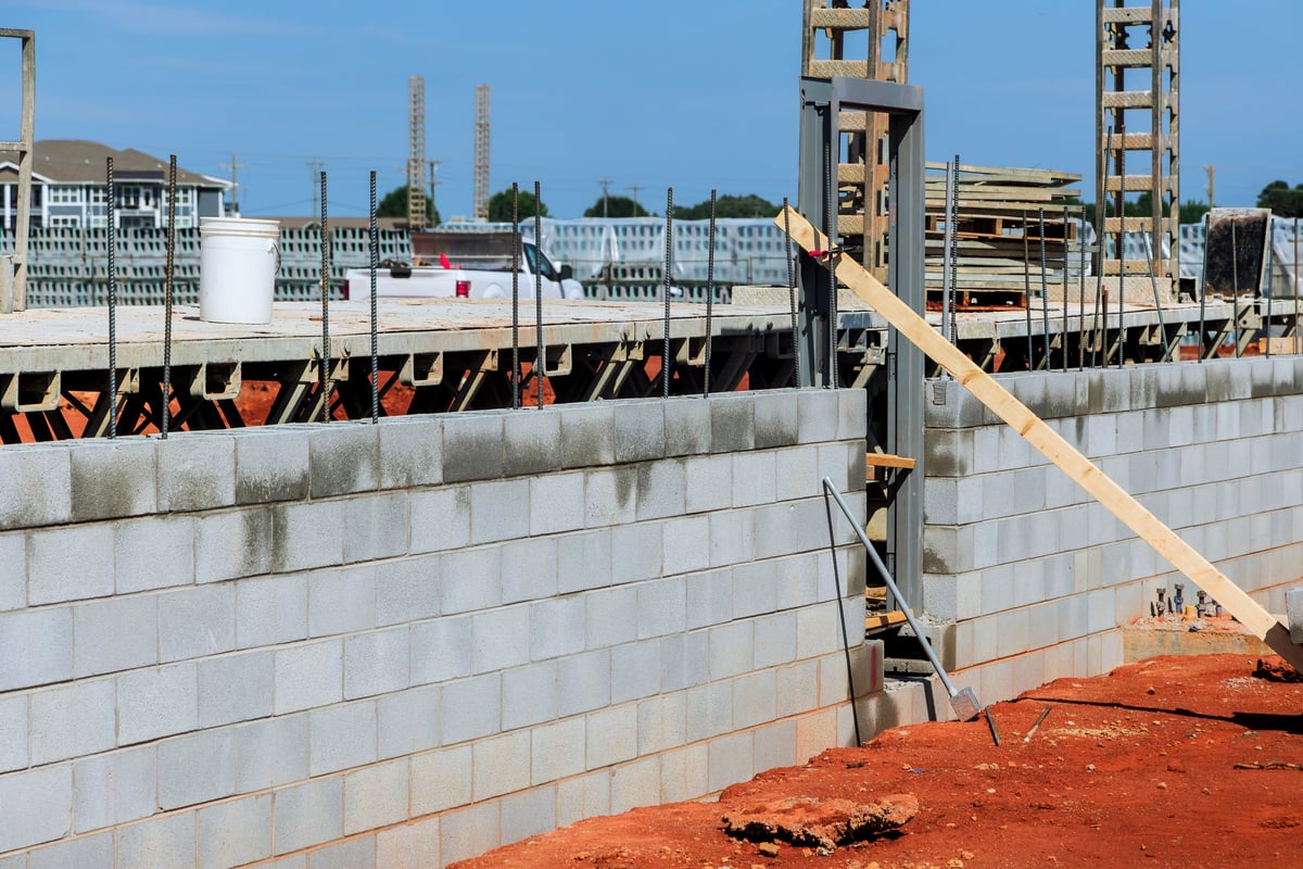 Workers are constructing masonry wall at construction site with materials arranged for ongoing building efforts