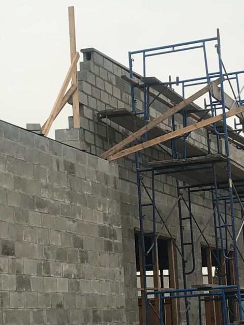 Construction site with concrete block wall and blue steel scaffolding with wooden beams